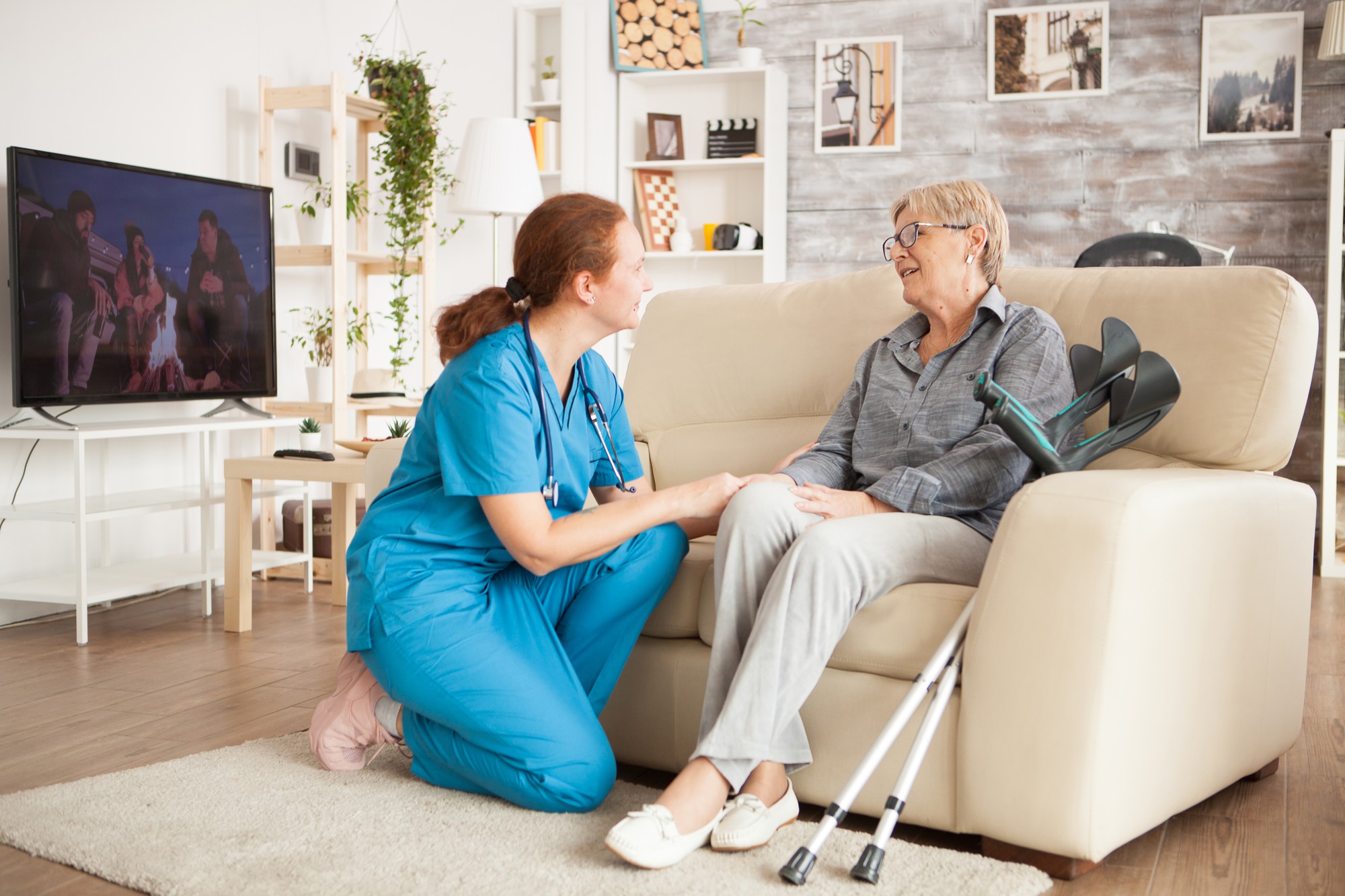 young-female-nurse-wearing-blue-uniform-talking-with-senior-woman-nursing-home